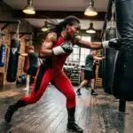 Boxeuse en rouge frappant un sac de boxe noir