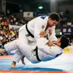 Deux judokas en blanc s'affrontent lors d'une compétition officielle.